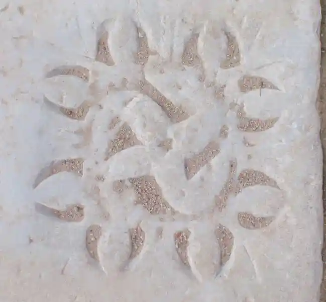 Rounded swastika with sun flares engraved on marble stone